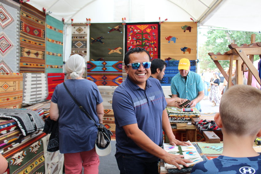 Zapotec weaver Mel Mendez, center, showcases his pieces at the Golden Fine Arts Festival Aug. 20 in downtown Golden. Mendez, who's from Prescott, Arizona, was the featured artist at this year's festival. The posters and T-shirts for the 32nd annual event feature his rug titled "Contemporary Fish."